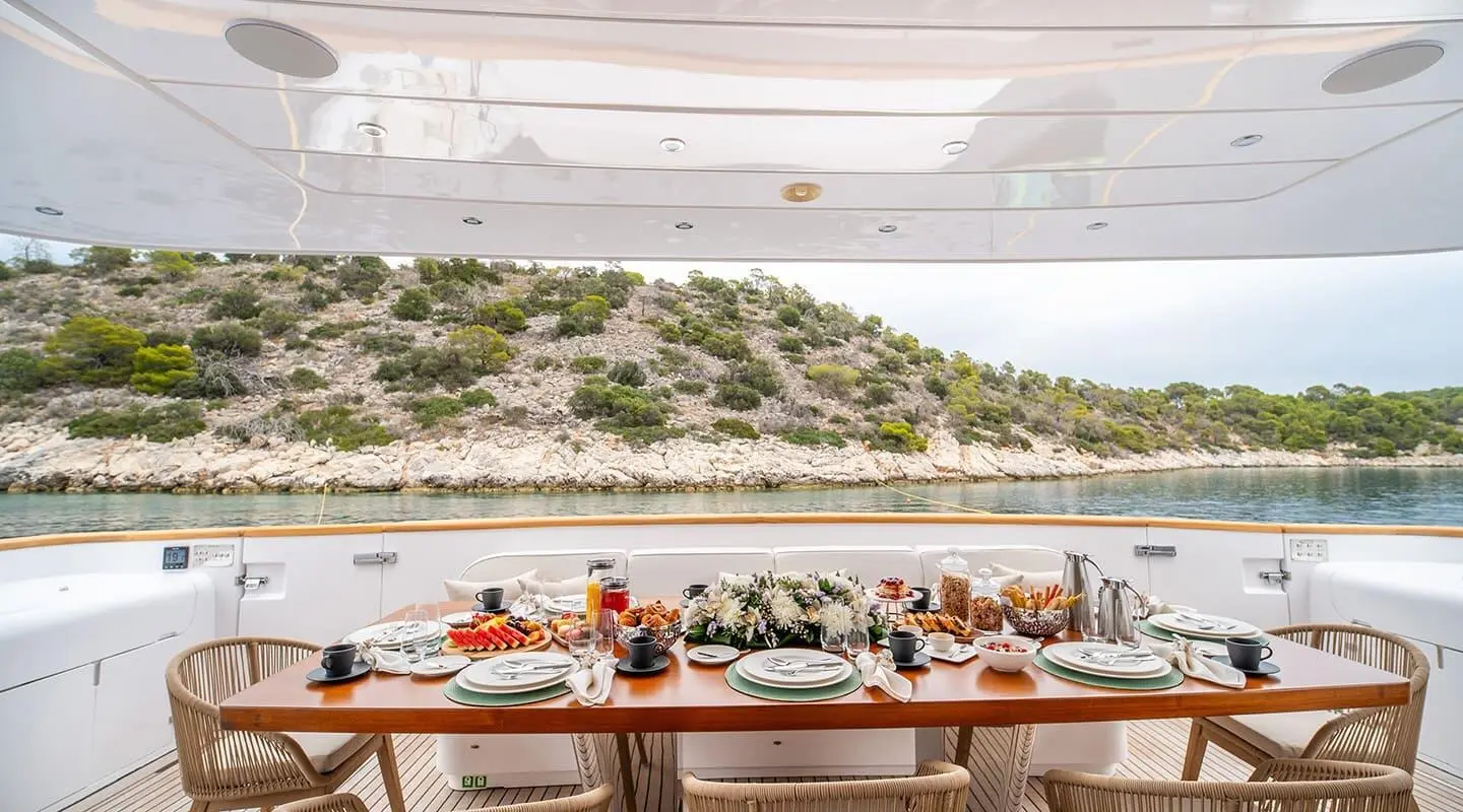 Pareaki II yacht on an open deck with a long dining table set for a meal