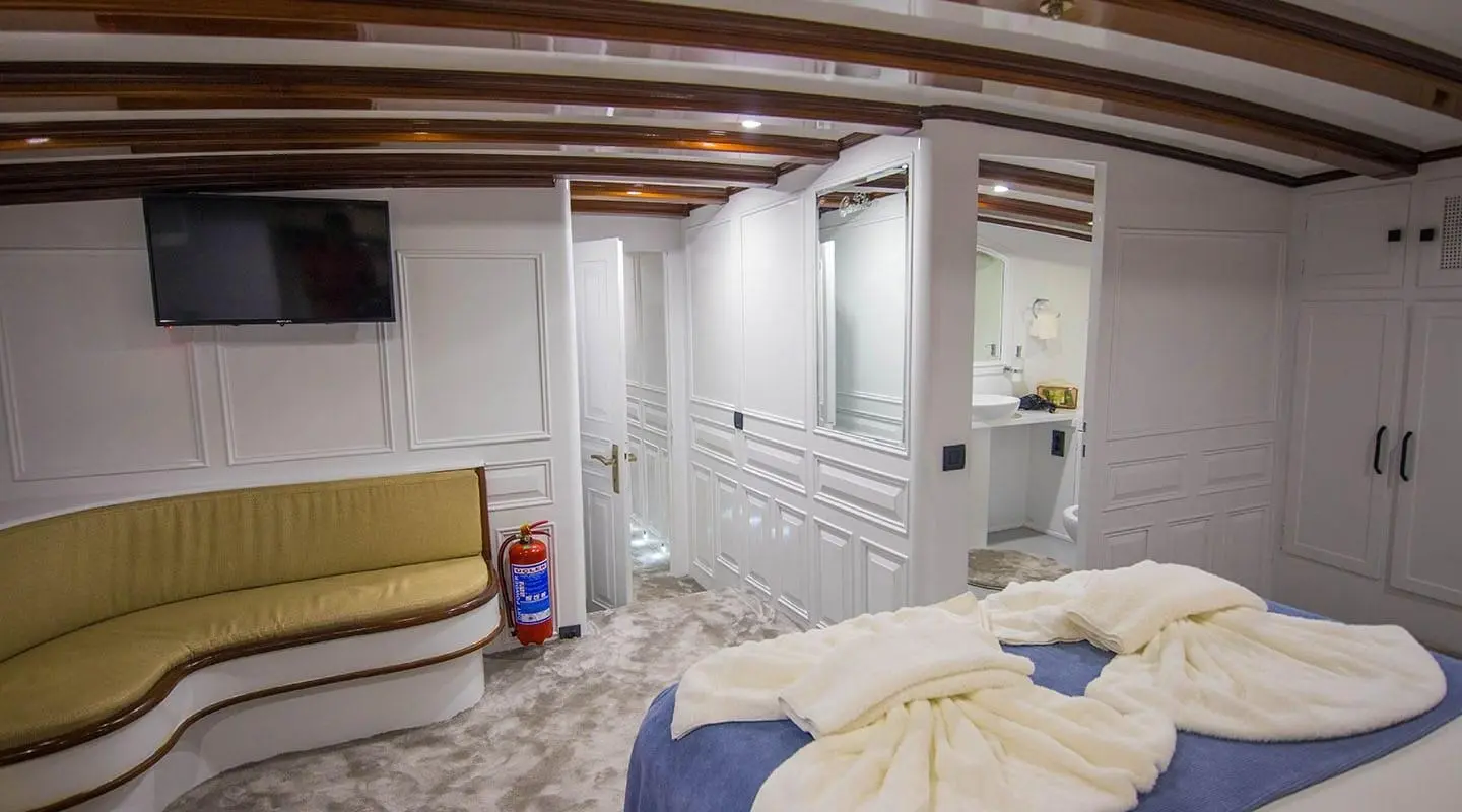 Indoor yacht cabin with bunk beds, storage cabinets, and a small seating area