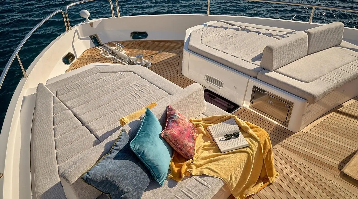 Top deck seating on a yacht with colorful cushions and sunlit wooden deck