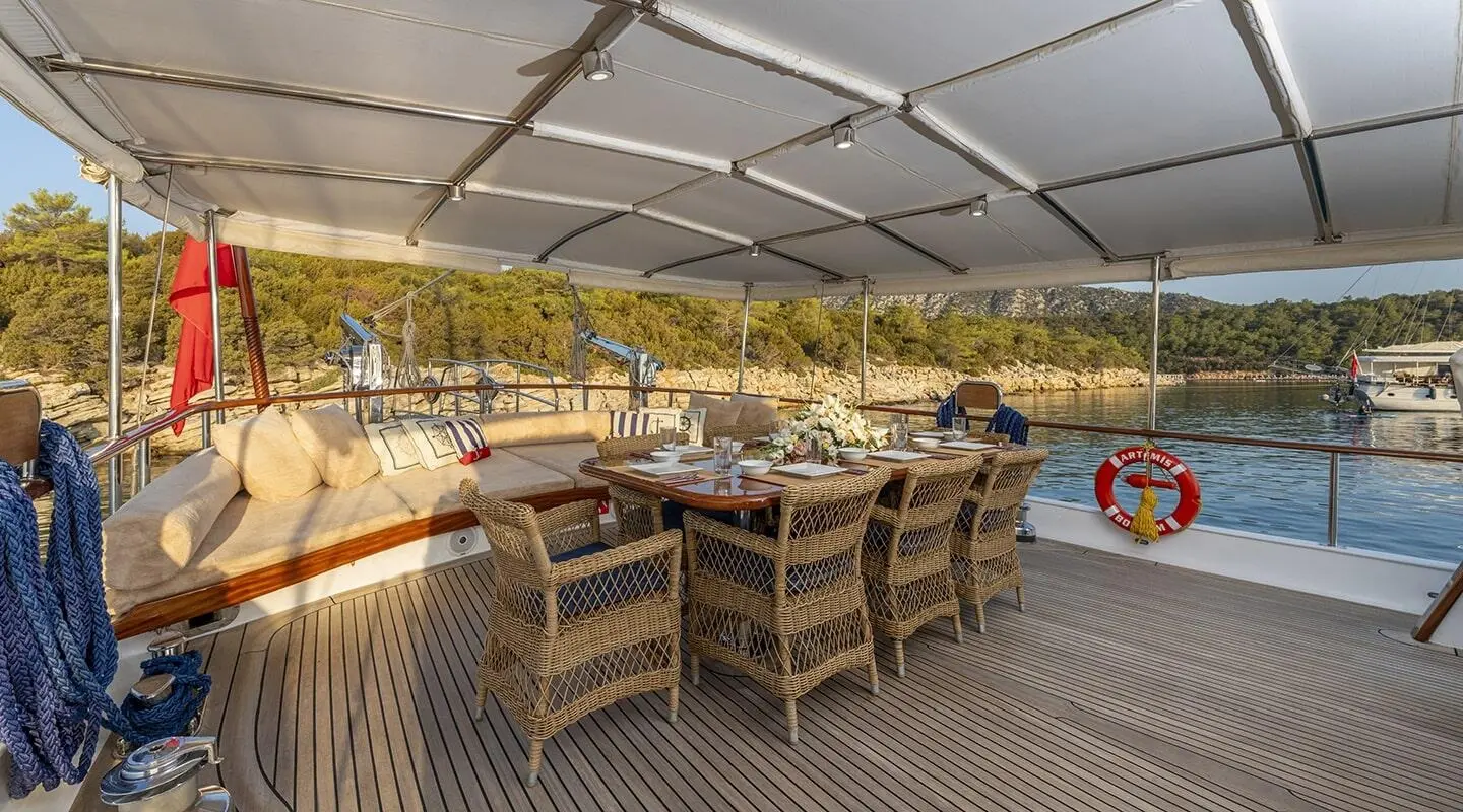Artemis yacht aft deck dining under canopy with wicker chairs set for alfresco meal