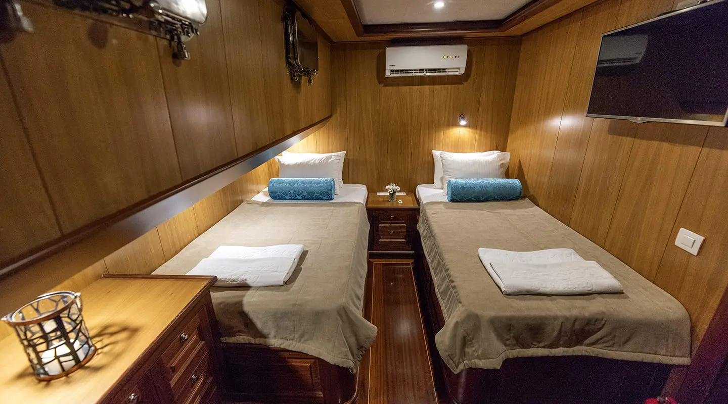 Kayhan 3 yacht interior with twin beds, wood panels, and cabin lighting