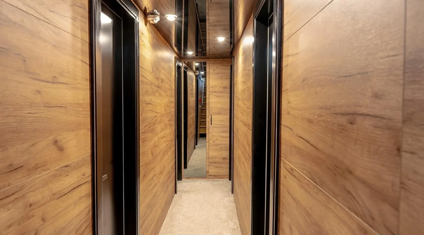 Wood-paneled corridor inside with doors and mirrors along a narrow hallway