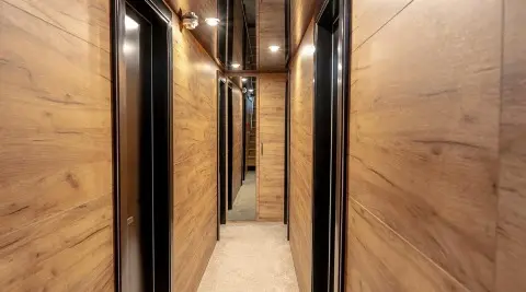 Wood-paneled corridor inside with doors and mirrors along a narrow hallway