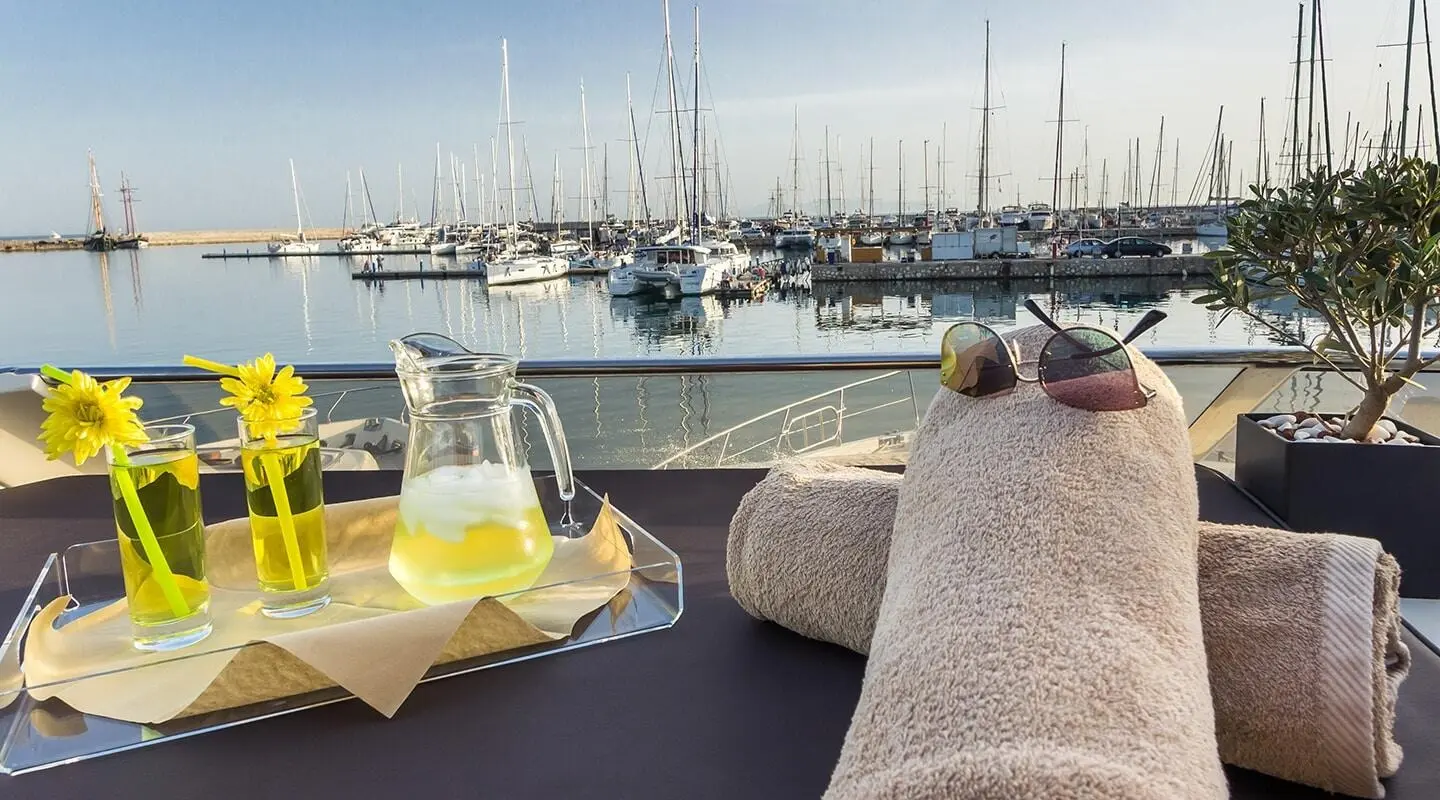A luxury yacht Amoraki deck view with loungers, table, and marina beyond