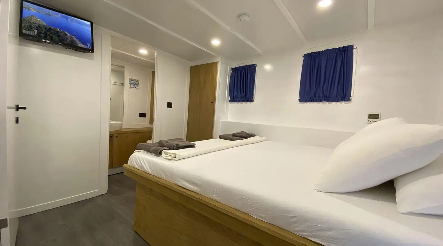 Maske 5 gulet cabin interior with double bed and blue artwork on wall