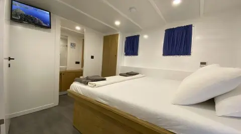 Maske 5 gulet cabin interior with double bed and blue artwork on wall