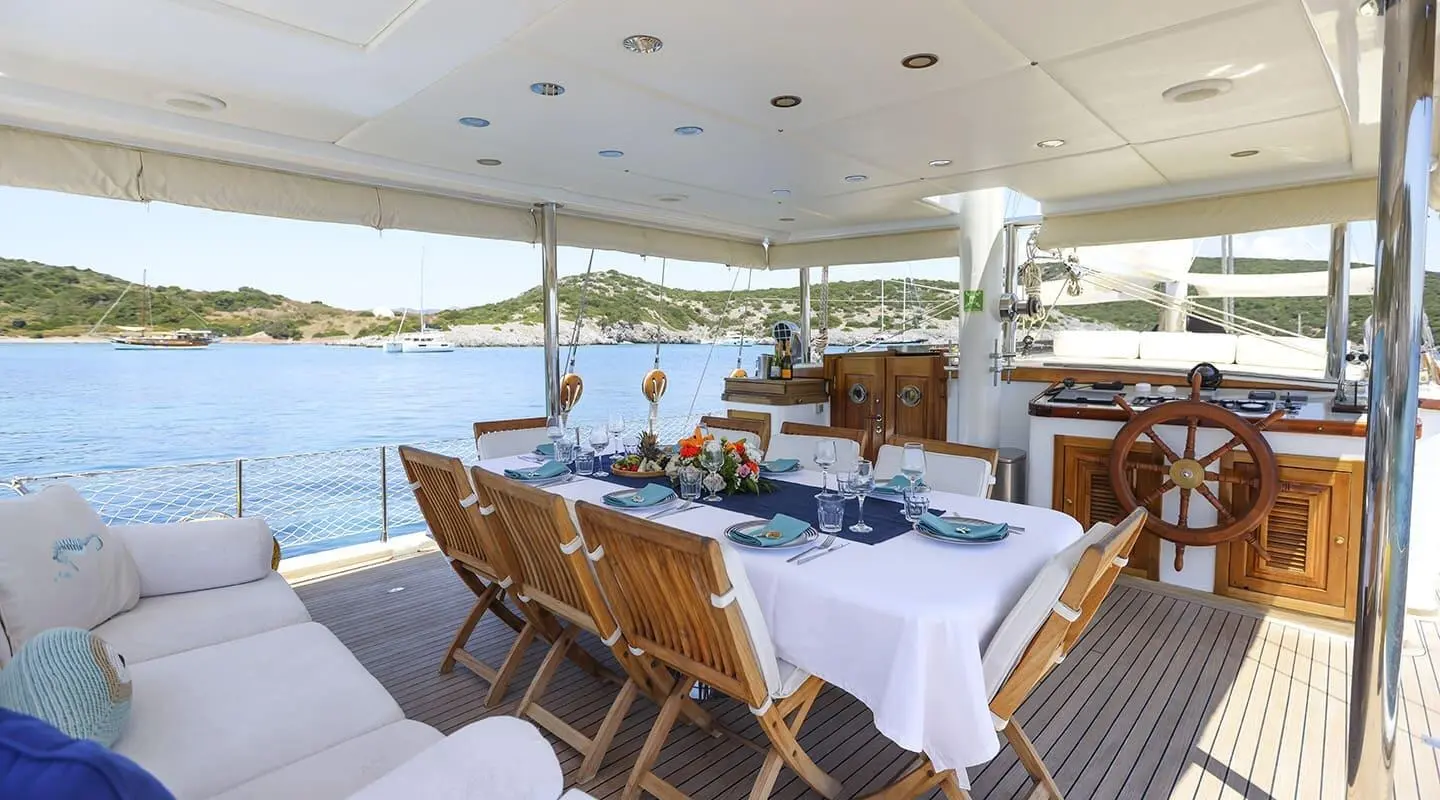 Gazella yacht dining area on deck with chairs, tableware, and sunset water views