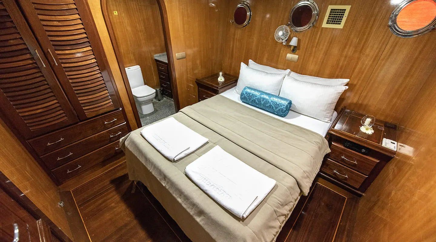 Kayhan 8 yacht cabin interior with bed, towels, warm lighting
