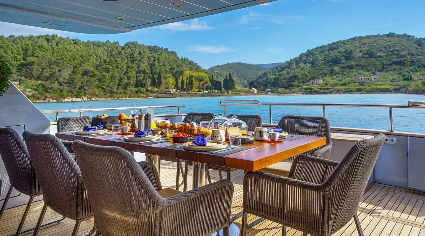 Phantom yacht dining area on deck, sunset light, table settings and wicker chairs