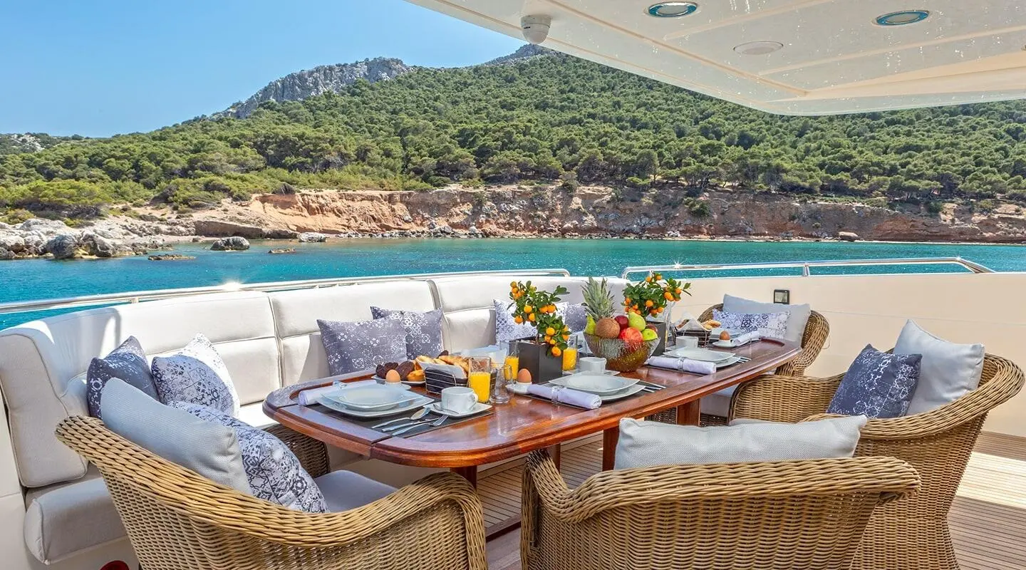 Divine yacht dining setup on deck at sunset with wooden tables and wicker chairs
