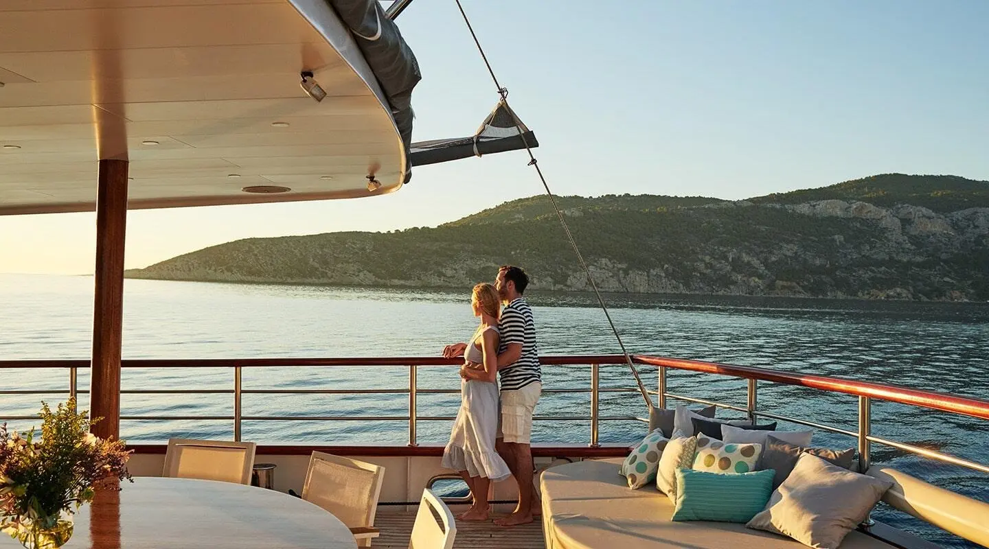Yacht Corsario on calm sea at sunset with passengers on deck