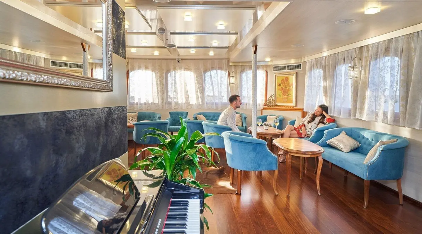 Casablanca yacht lounge area with blue chairs, wooden floor, and plants