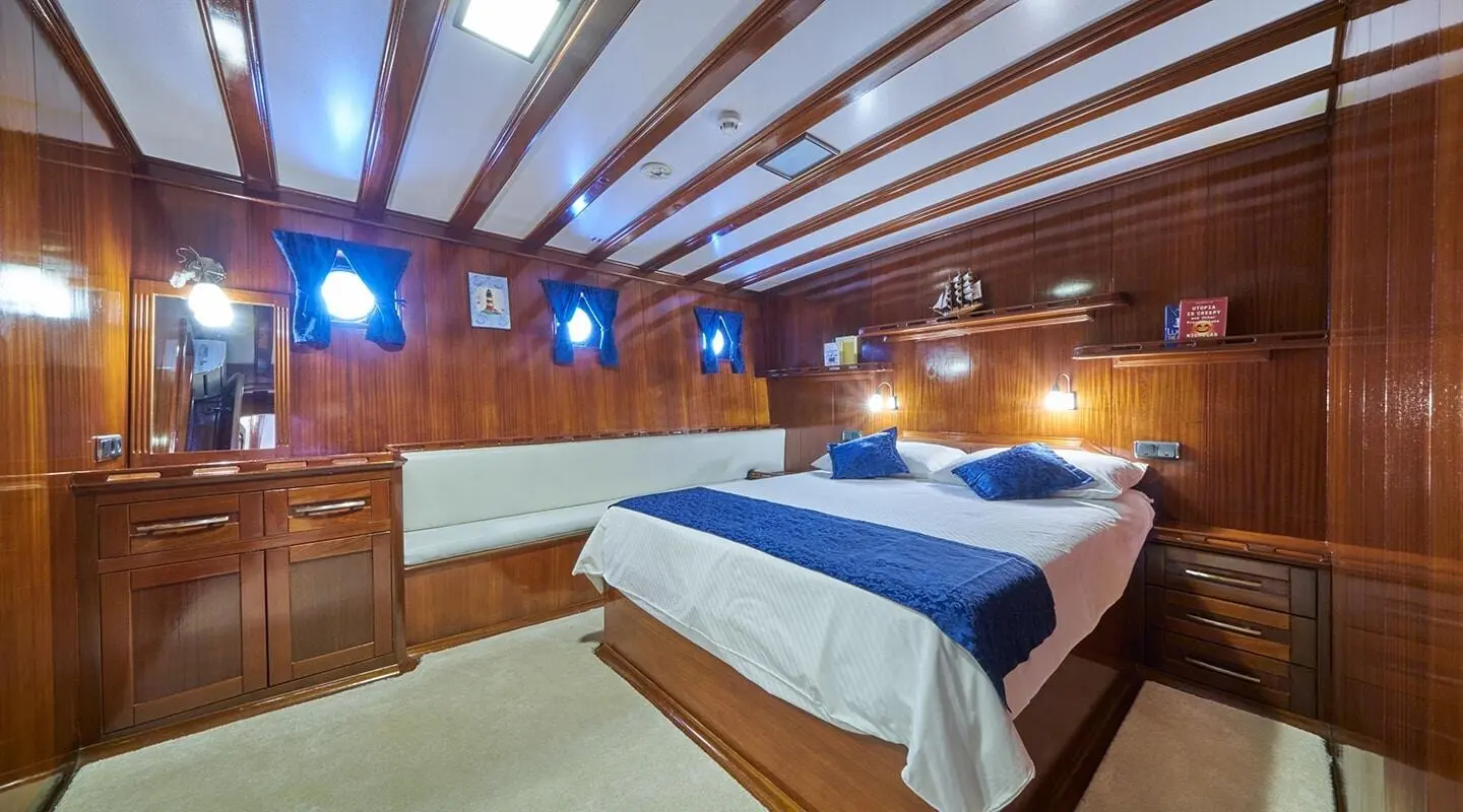 Gulet Stella Maris bedroom with two single beds and blue bedding, wood-paneled cabin