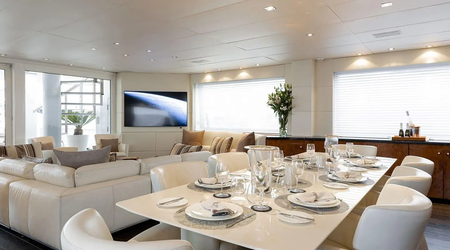 Indoor yacht dining area on Brooklyn with set table, chairs, and soft lighting