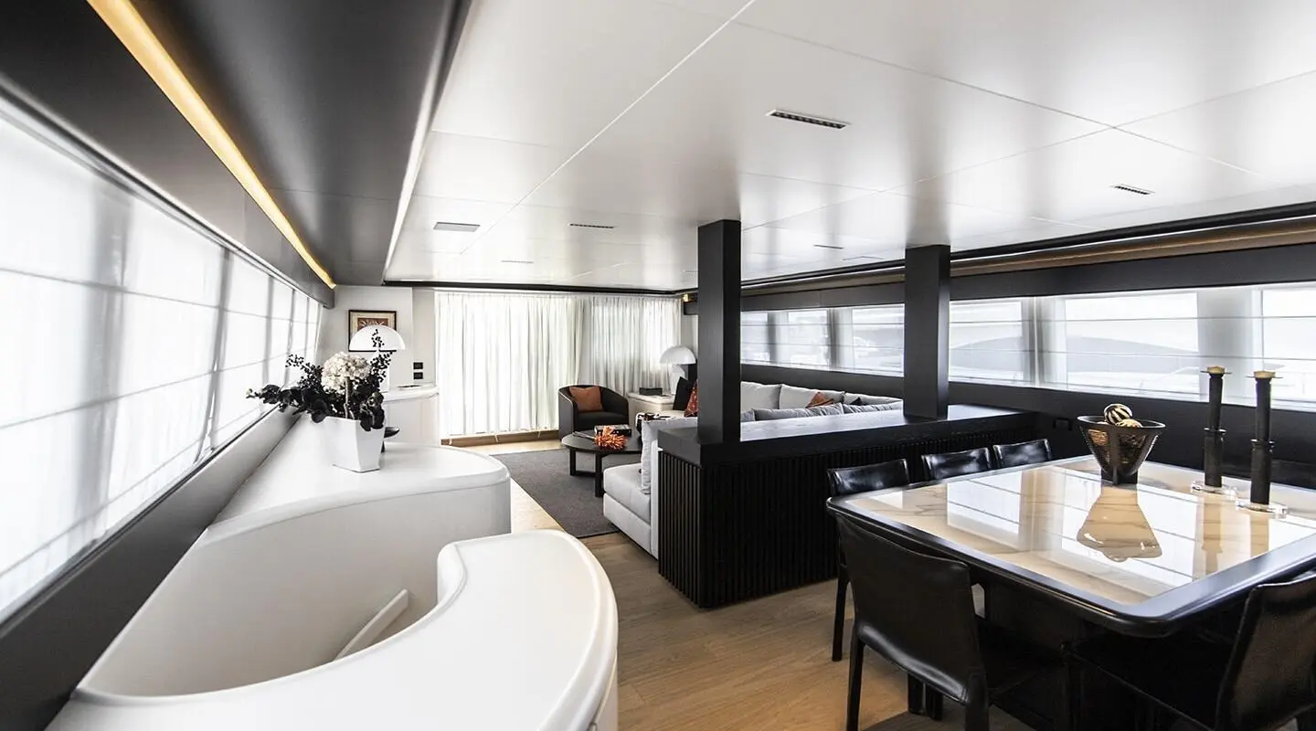Luxurious yacht salon with curved seating, large windows, and a table setup
