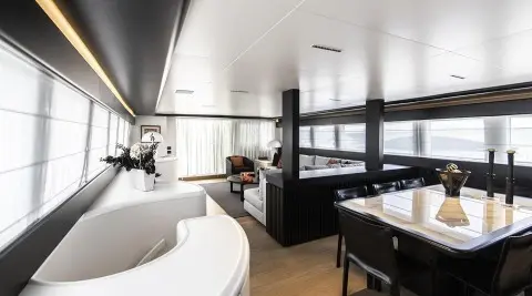 Luxurious yacht salon with curved seating, large windows, and a table setup