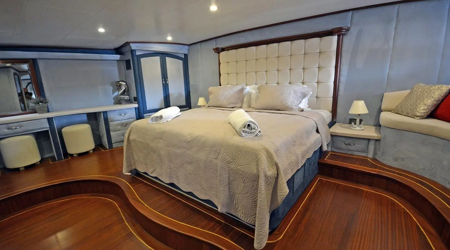 Bella Mare master cabin aboard gulet, queen bed, wooden floor, beige headboard