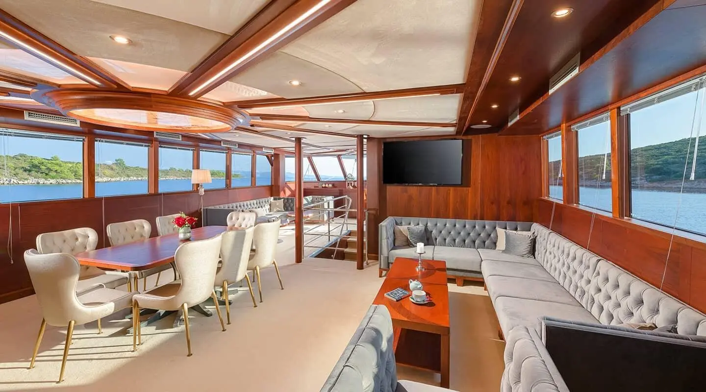 Interior of Lady Gita yacht salon with seating, wooden cabinetry, and windows