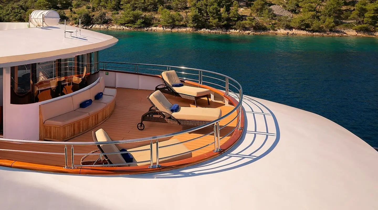 Queen Eleganza yacht deck at sunrise with sun loungers and railing