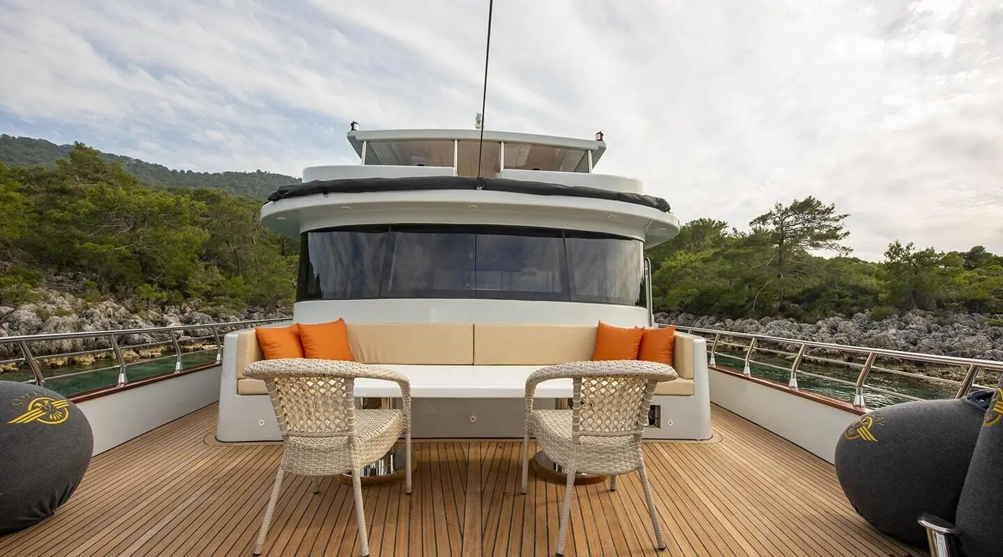 Simay M yacht moored, teak deck, two chairs, white exterior, calm water backdrop