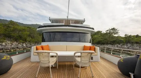 Simay M yacht moored, teak deck, two chairs, white exterior, calm water backdrop
