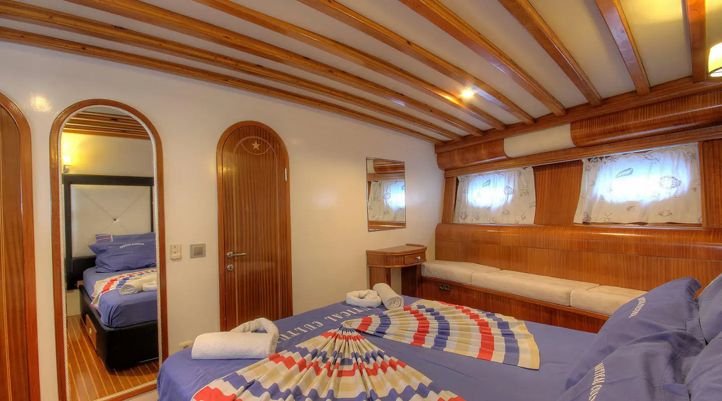 Angelo II master cabin with wood paneling, bed, and porthole windows