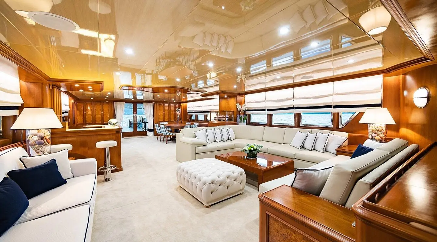 Luxurious yacht Wind Of Fortune salon with cream seating, wooden shelves, and warm lighting