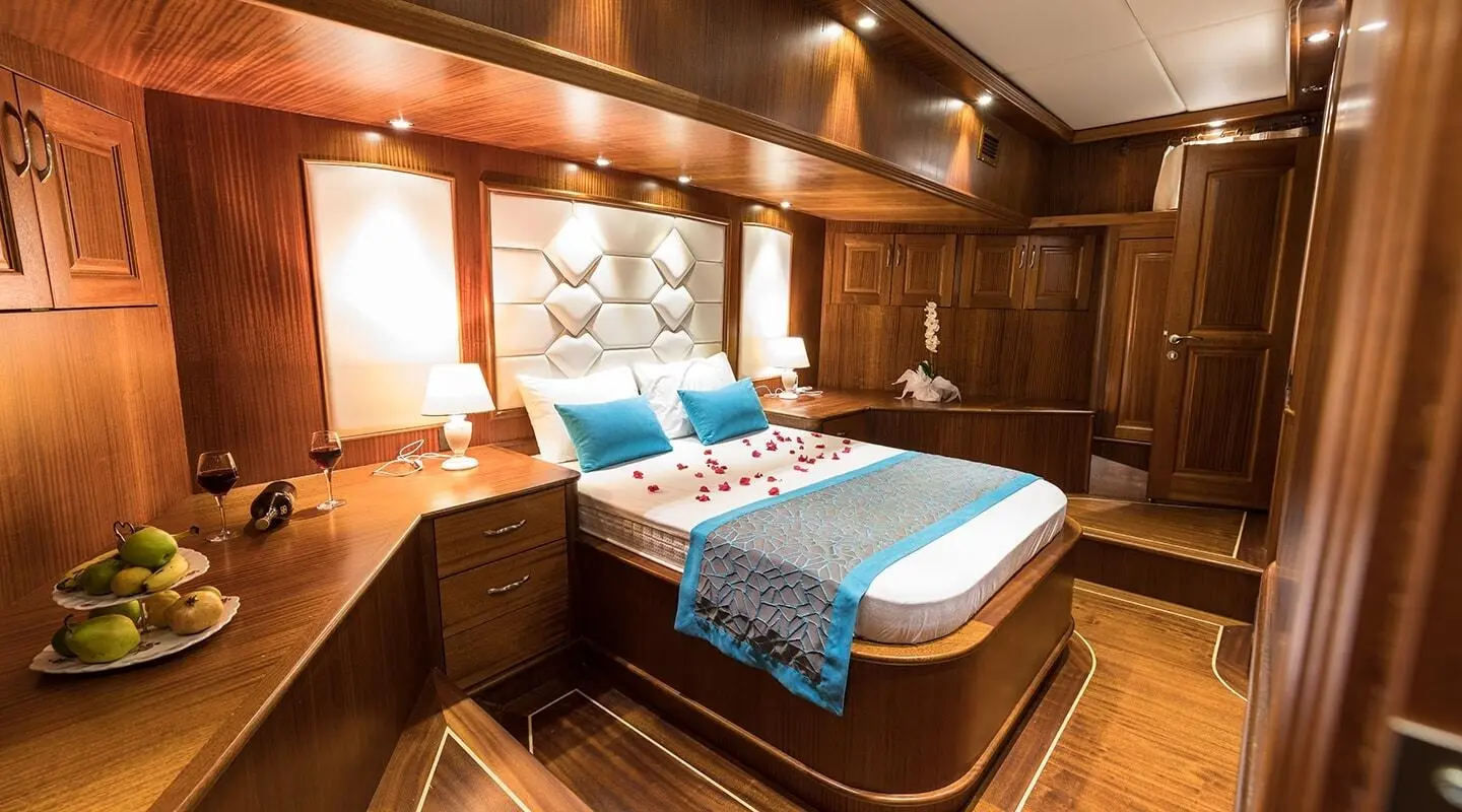 Master cabin aboard Vista Mare yacht with bed, blue bedding, wood panels