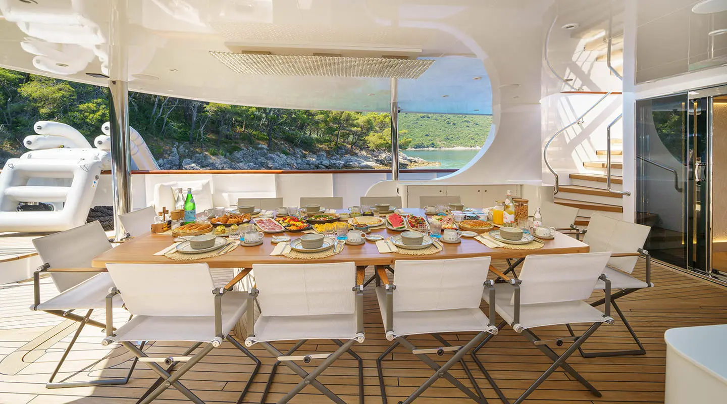 Maia yacht dining area with a long table set for guests onboard