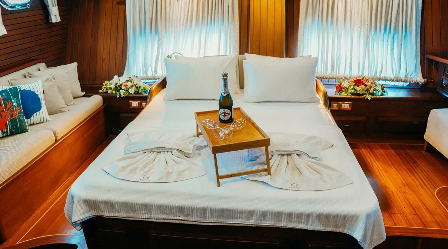 Luxurious yacht Wicked Felina bedroom with a bed, pillows, bedside lamps, and a wooden tray on the bed.