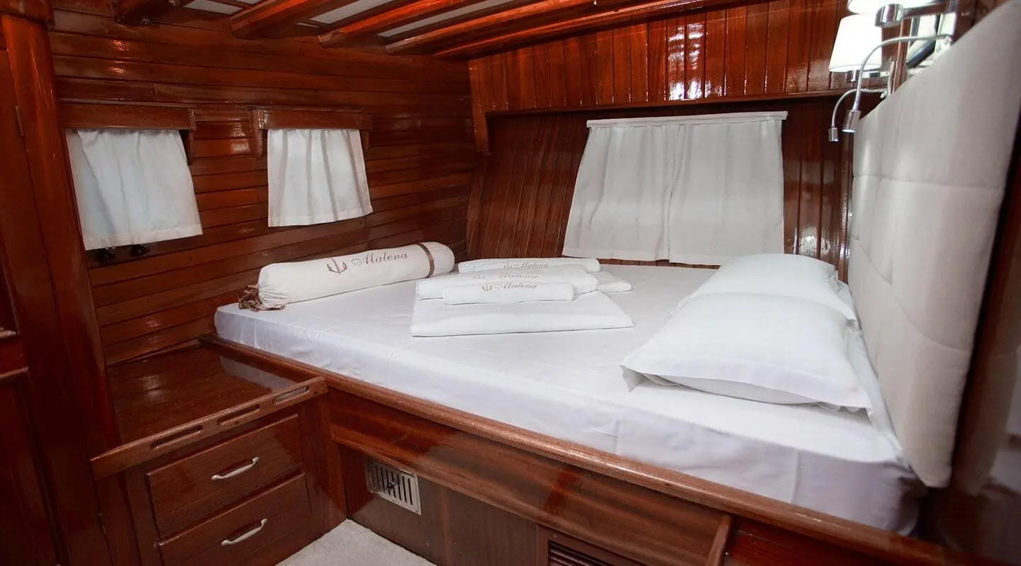 Cozy, polished wooden bunk cabin on Malena yacht with white bedding and cushions