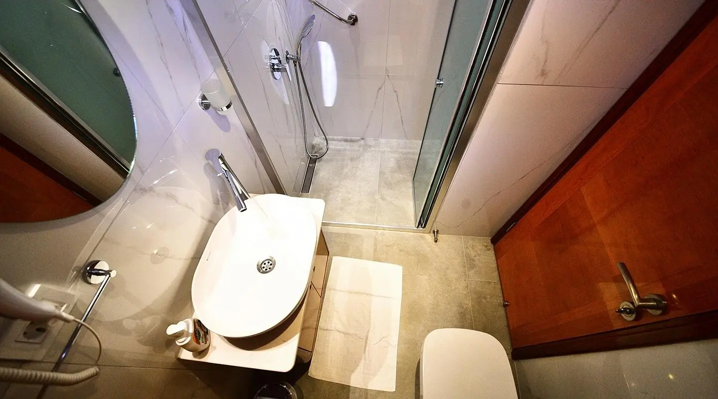 Small bathroom aboard Maya yacht with toilet, sink, and shower stall
