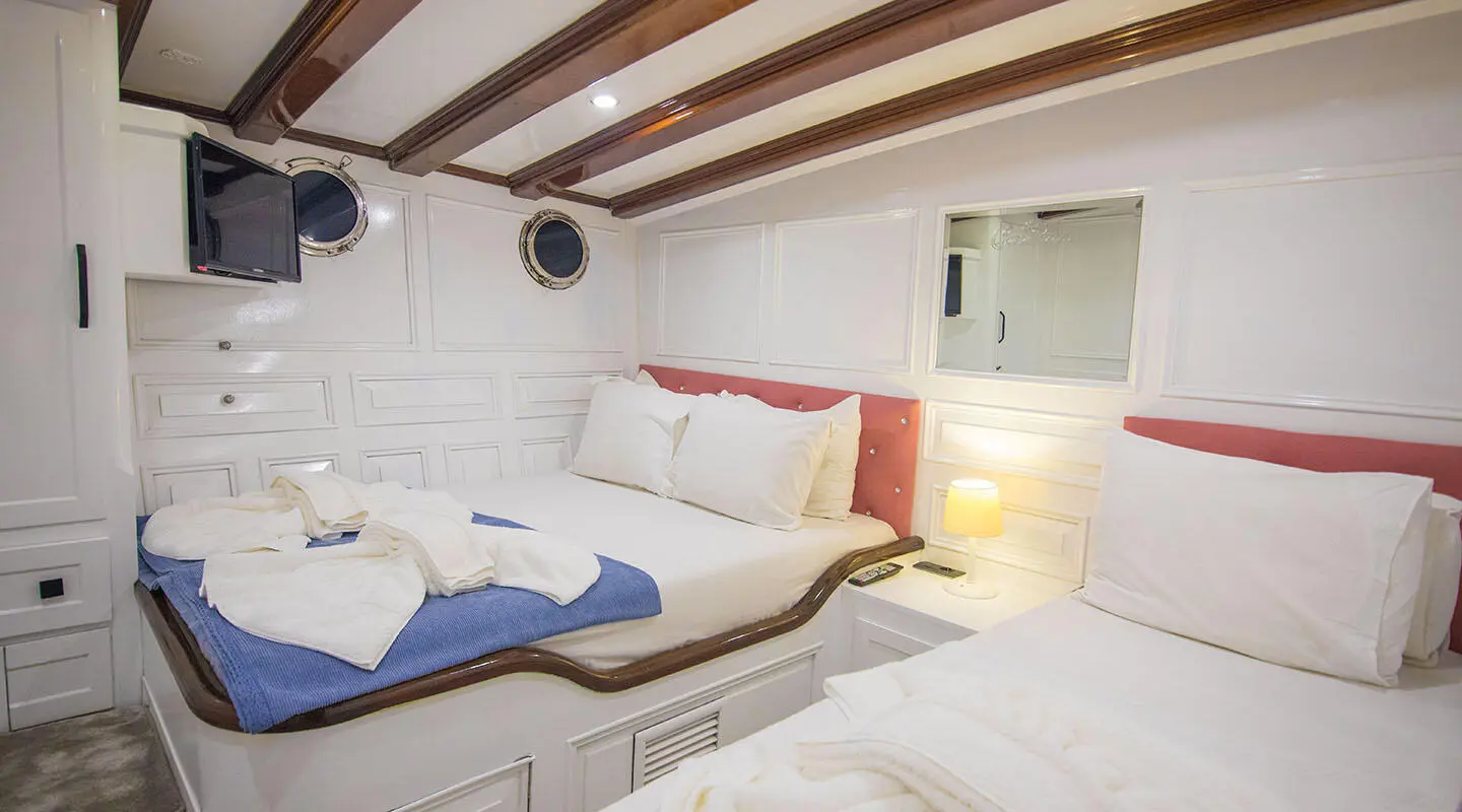 Interior of Grande Mare yacht with twin cabins and seating area, blue and white cushions