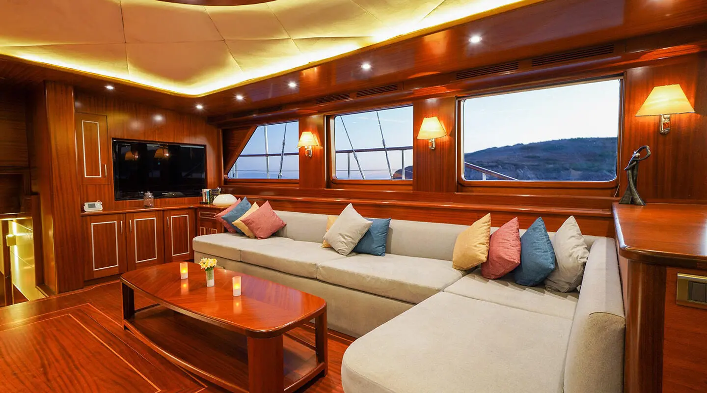 Luxurious yacht saloon with cream seating, wooden cabinetry, and teal cushions