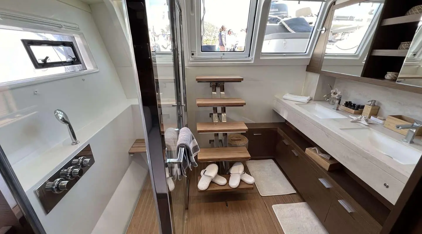 Interior yacht bathroom with wooden steps, white tiles, and a compact sink area