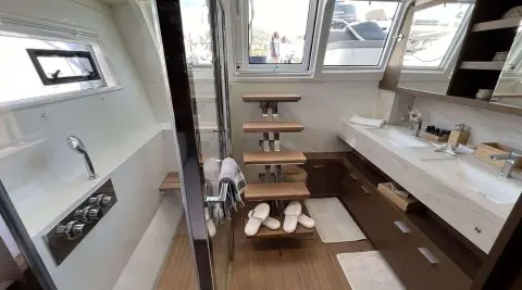 Interior yacht bathroom with wooden steps, white tiles, and a compact sink area