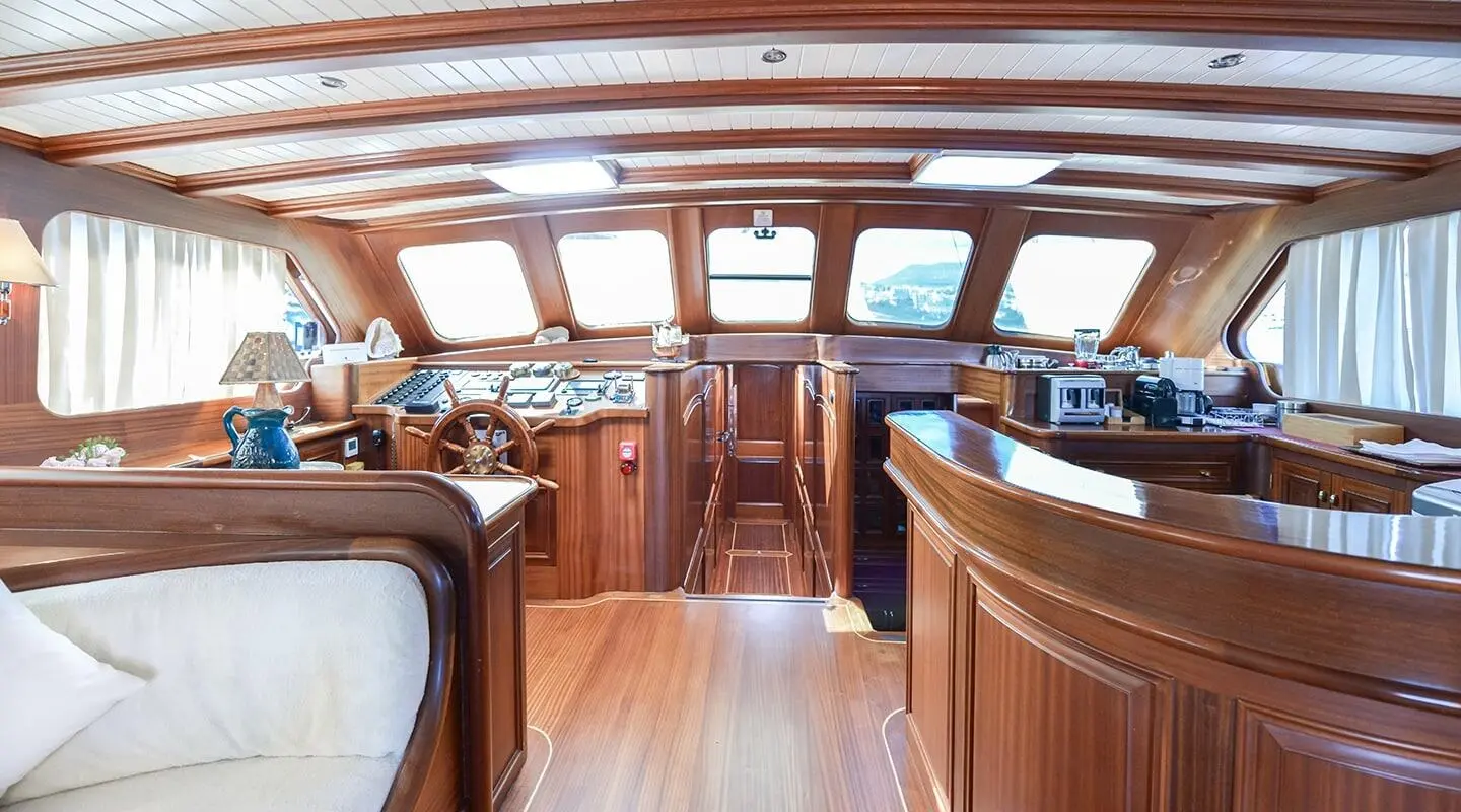 Luxurious yacht interior with wooden cabinetry, seating, and helm area aboard Lady Christa at sunset
