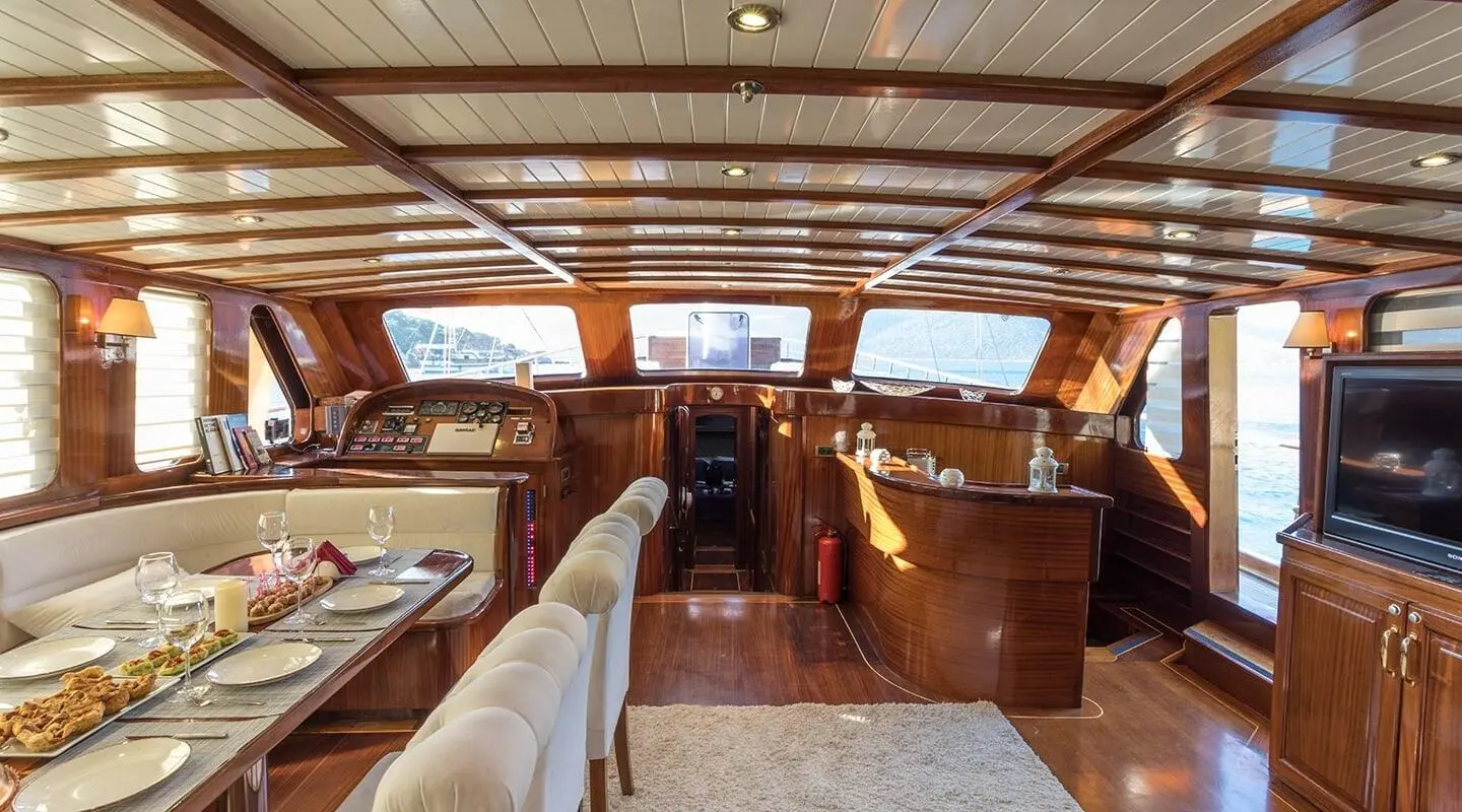 Luxury wooden yacht interior with a bar area and dining table in foreground