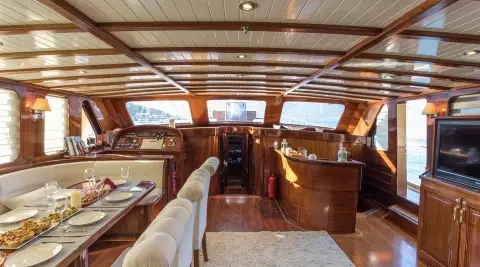 Luxury wooden yacht interior with a bar area and dining table in foreground