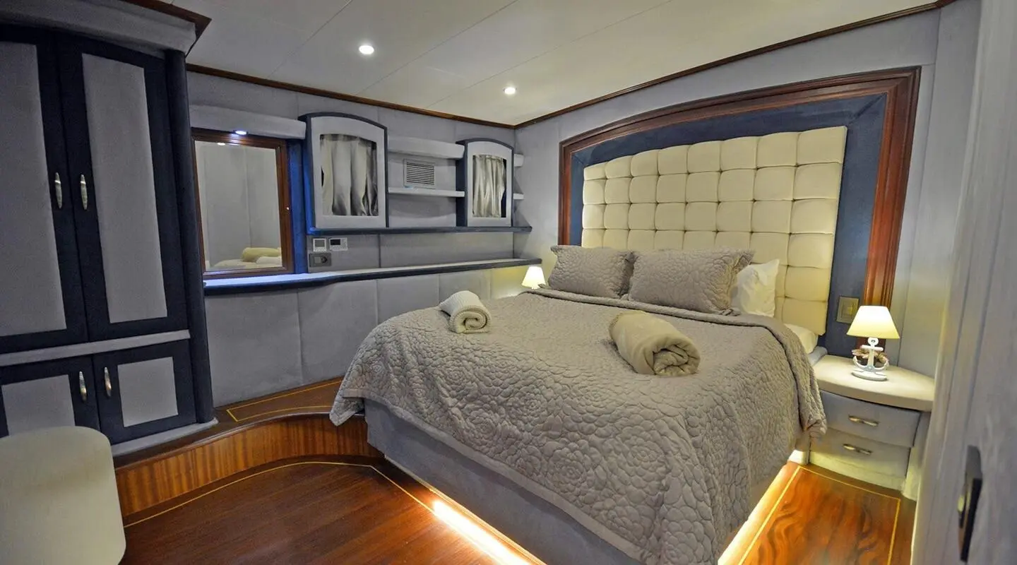 Bella Mare yacht interior: well-lit cabin with two beds, framed headboard, and soft bedding