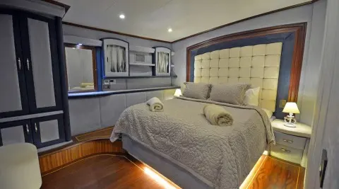 Bella Mare yacht interior: well-lit cabin with two beds, framed headboard, and soft bedding