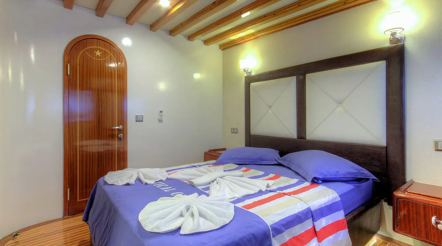 Angelo II luxury yacht cabin with tufted headboard and striped bedspread