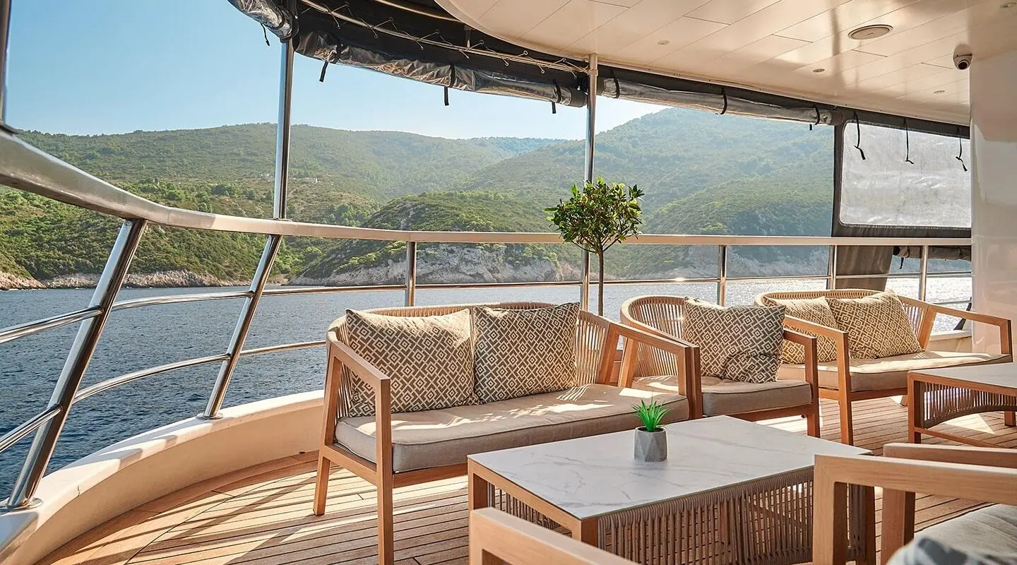 Lupus Mare yacht lounge area with wooden chairs and small table on deck under shade