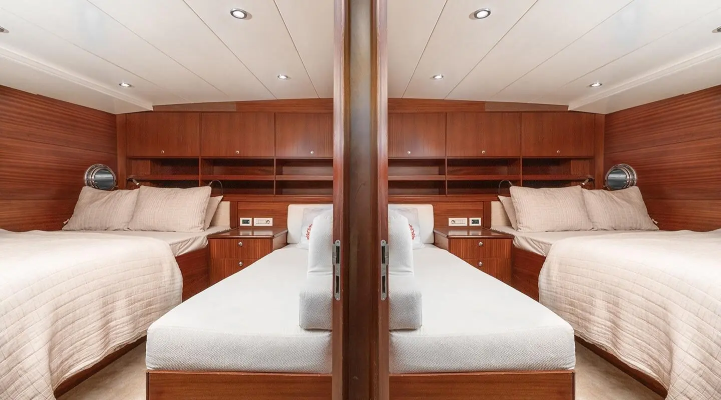 Interior view of a luxury yacht with twin cabins, wooden cabinetry, and neatly made beds