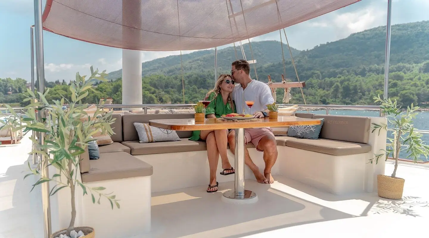Cesarica yacht on a sunny deck with two people seated at a wooden table