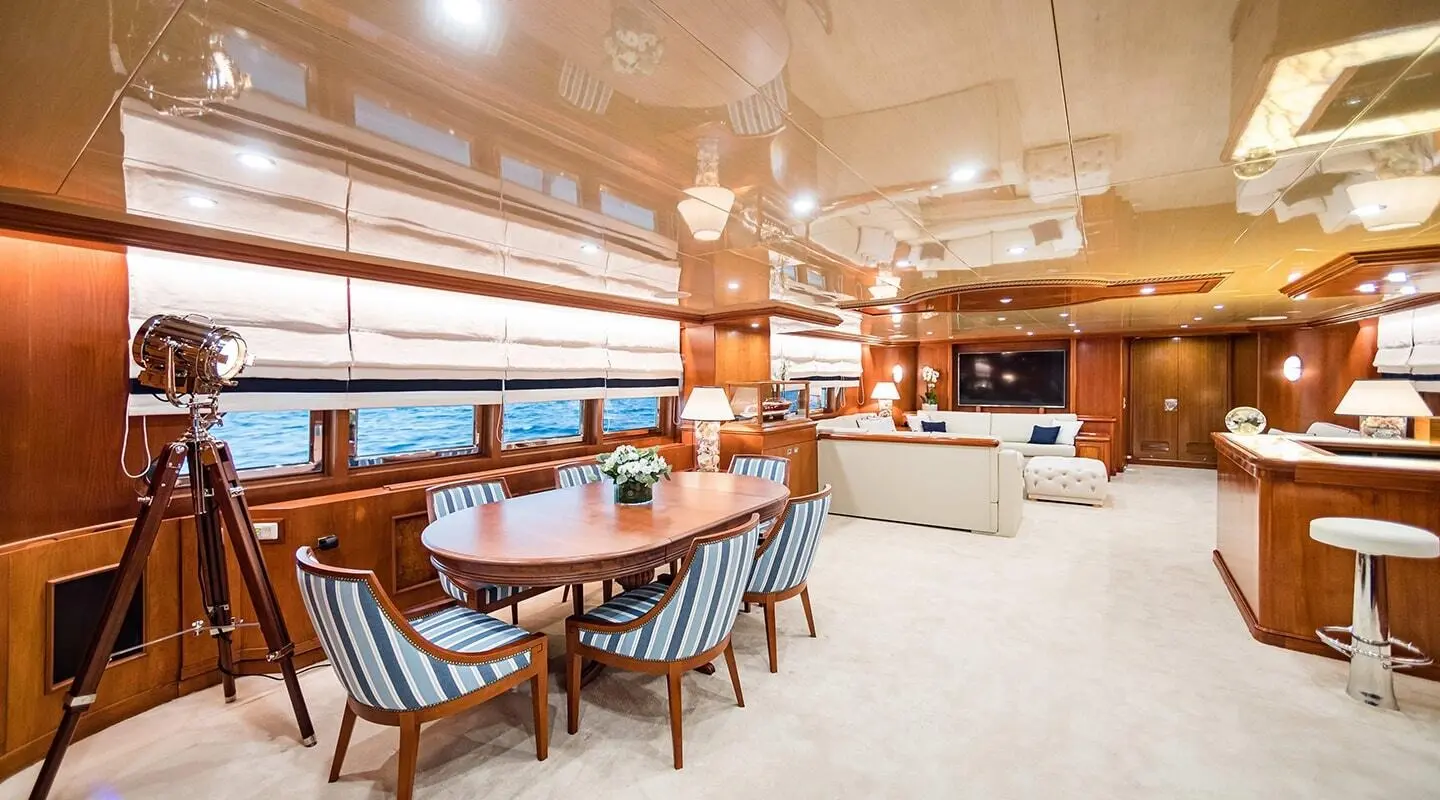 Interior lounge of Wind Of Fortune yacht with wooden tables and blue chairs