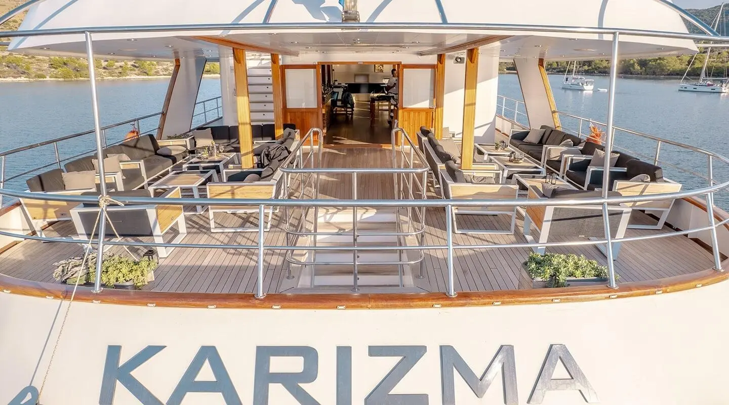 Karizma yacht exterior upper deck lounge with seating and helm, ocean backdrop