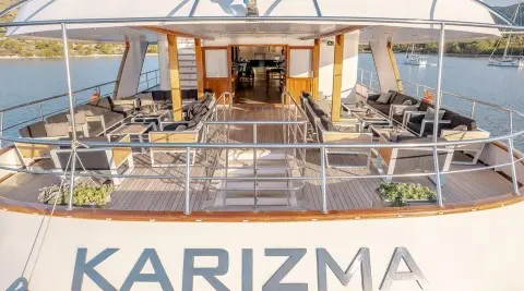 Karizma yacht exterior upper deck lounge with seating and helm, ocean backdrop