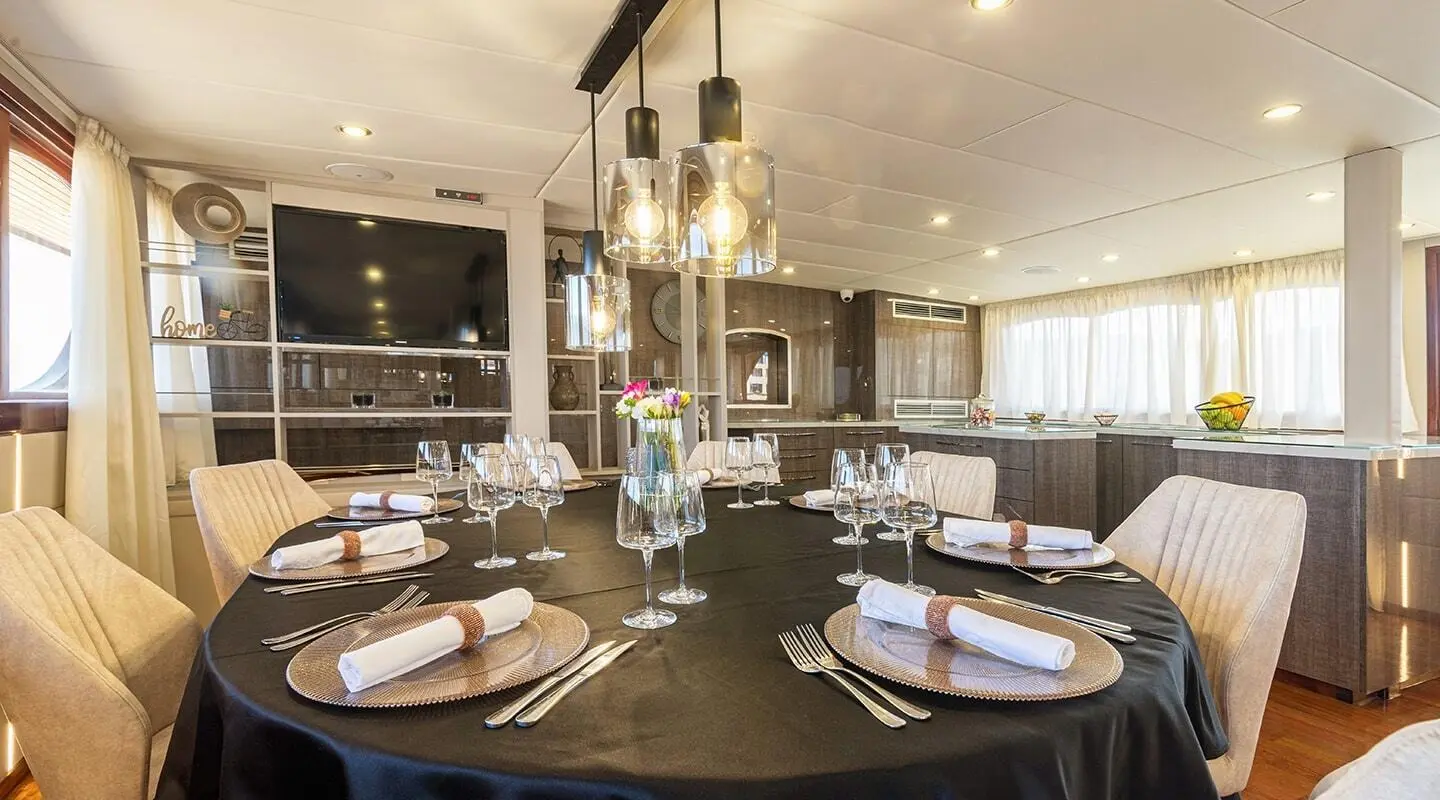 Inside Melody yacht saloon with round dining table set for drinks and candles