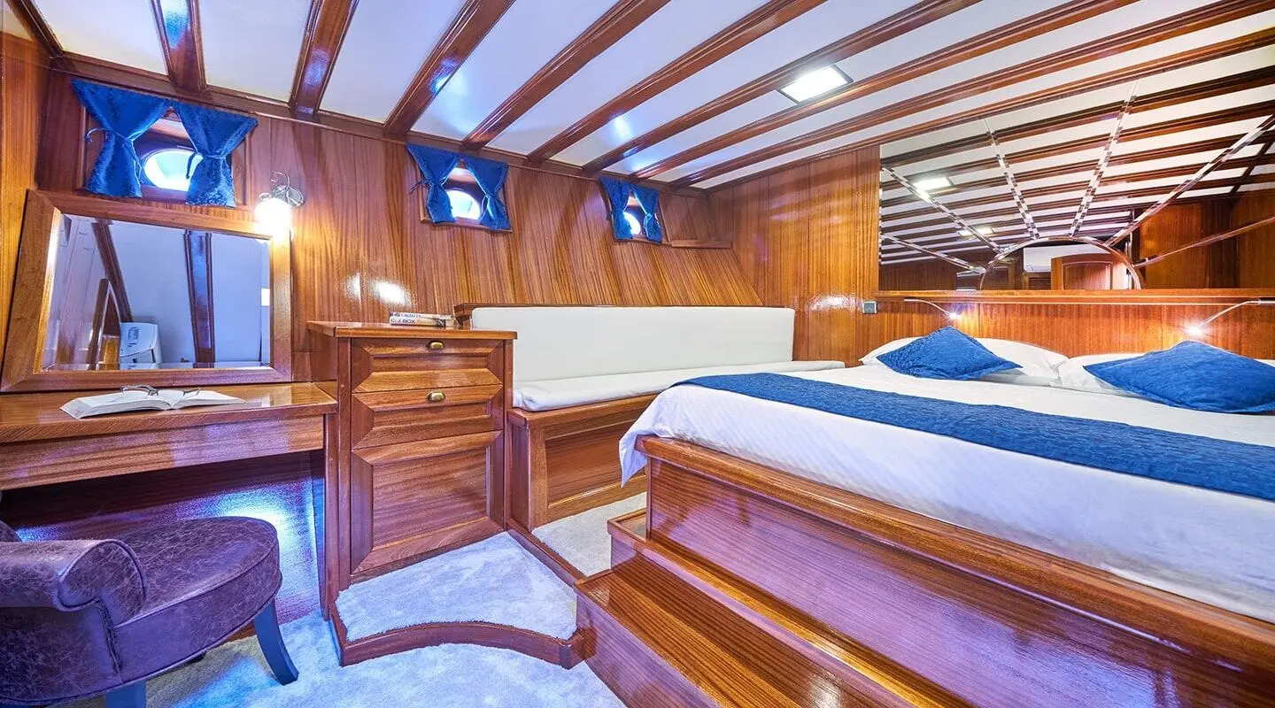 Stella Maris yacht interior with polished wooden panels, bed, and ambient warm lighting